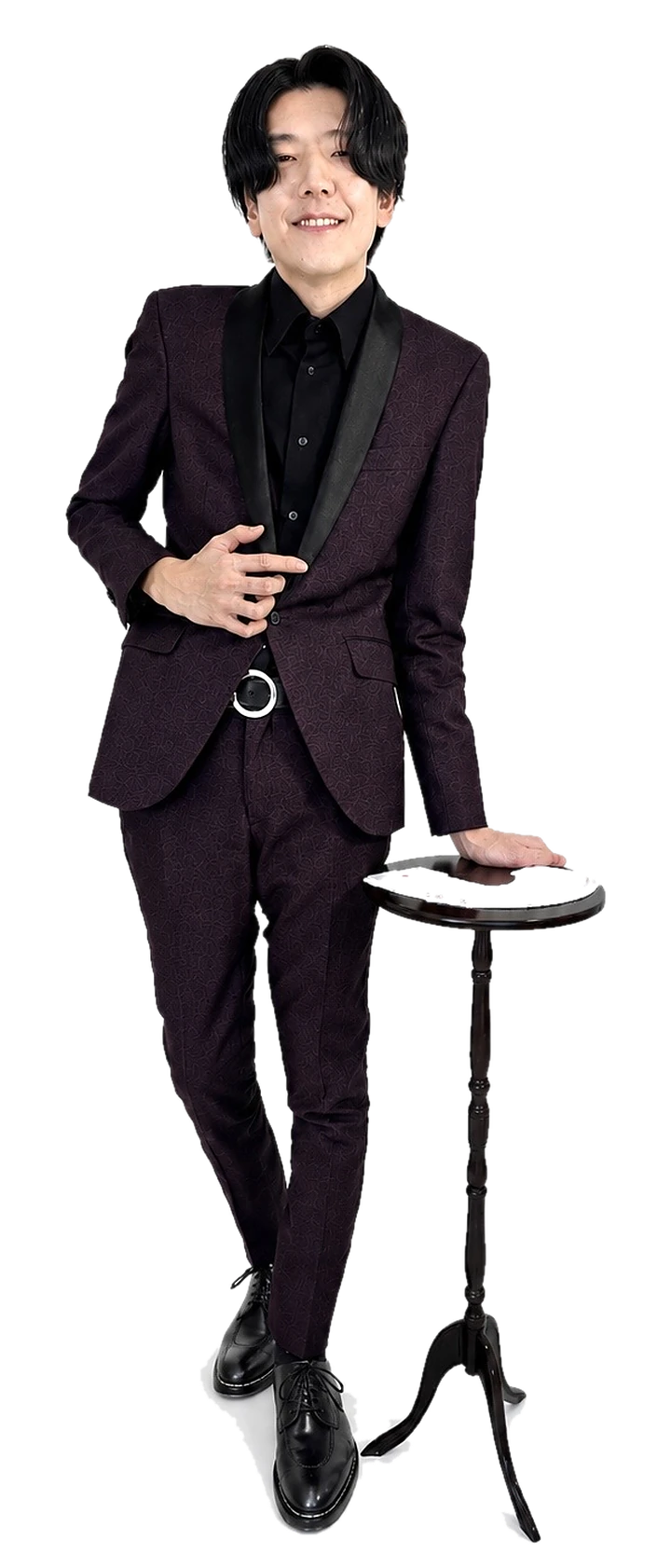 タキシード姿でカードのテーブルに手を添えるマジシャン藤田大知