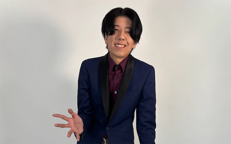 スーツ姿で手を差し出し笑顔を見せる藤田大知